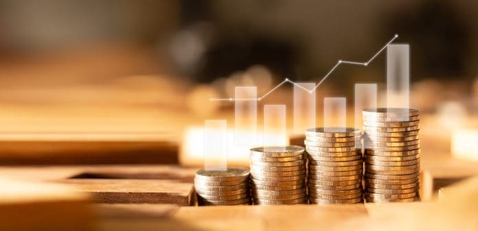 stacks of coin of varying heights on a table with an aminated graph behind it.
