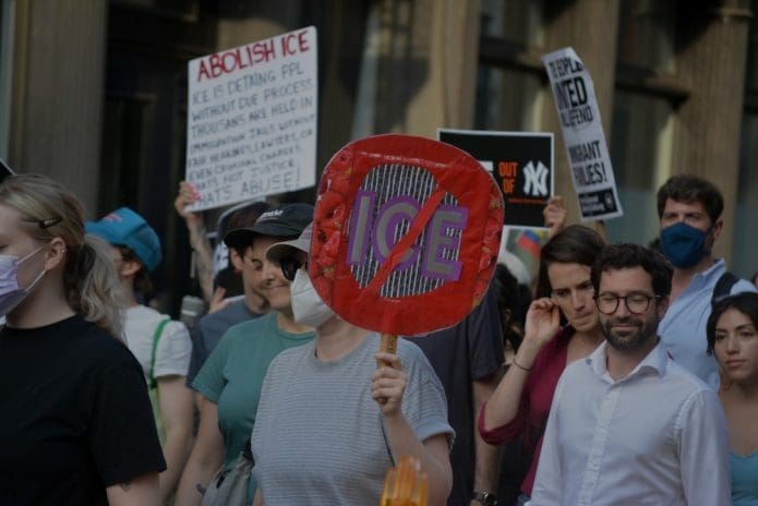 Demonstrators hold signs calling for the abolition of ICE.