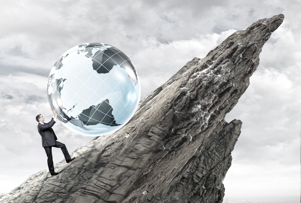 Composite stock photo of a man pushing a large globe up a steep rock